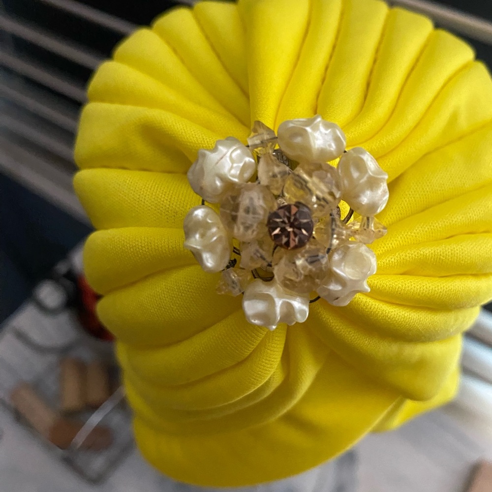 Sunny bright yellow cloche hat accented with a vintage jewelry piece